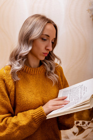 Woman at home on the couch reading a book. Home office. Remote Learning. High quality photoの写真素材