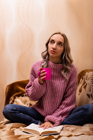Woman with book and tea sitting on sofa. Retro style. Knowledge Day. High quality photoの写真素材