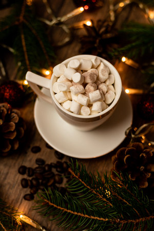 Marshmelon in a white cup on a table with Christmas lights. Christmas tree and cones on the table. High quality photoの写真素材
