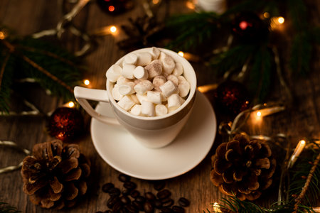 Marshmelon in a white cup on a table with Christmas lights. Christmas tree and cones on the table. High quality photoの写真素材