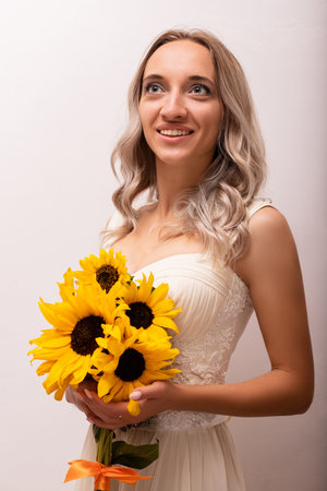 Bride in a wedding dress with a bouquet of sunflowers. Beautiful woman. Floristics. High quality photoの写真素材