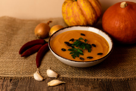 A bowl of pumpkin soup on the table. Autumn vegetables. Homemade food. Healthy nutrition. High quality photoの写真素材