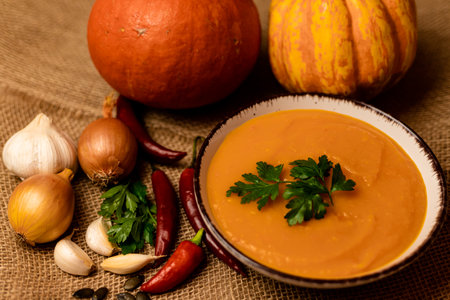 A bowl of pumpkin soup on the table. Autumn vegetables. Homemade food. Healthy nutrition. High quality photoの写真素材