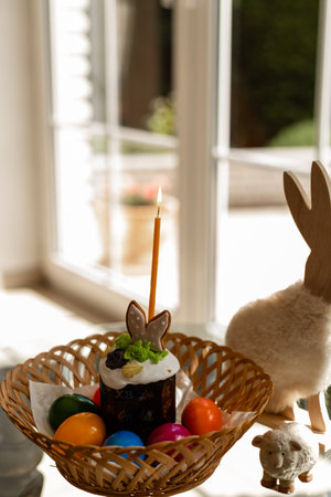 Easter cake with a lit candle. Easter colorful eggs in a basket on the table. High quality photoの写真素材
