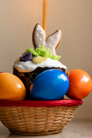 Easter cake with a lit candle. Easter colorful eggs in a basket on the table. High quality photoの写真素材