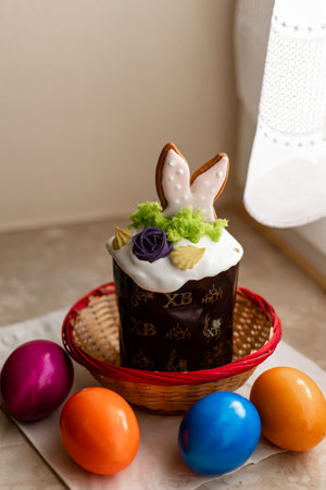 Easter cake with a lit candle. Easter colorful eggs in a basket on the table. High quality photoの写真素材