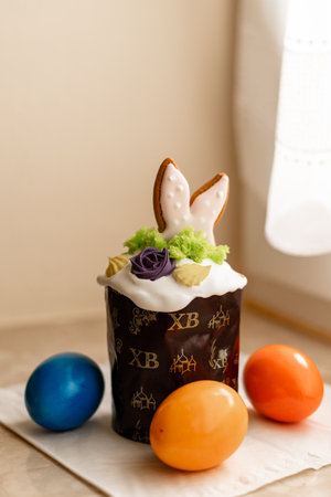 Easter cake with a lit candle. Easter colorful eggs in a basket on the table. High quality photoの写真素材