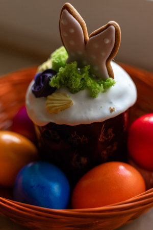 Easter cake with a lit candle. Easter colorful eggs in a basket on the table. High quality photoの写真素材