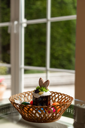 Easter cake with a lit candle. Easter colorful eggs in a basket on the table. High quality photoの写真素材
