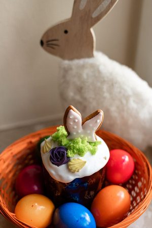 Easter cake with a lit candle. Easter colorful eggs in a basket on the table. High quality photo
