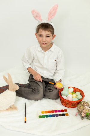 Little Boy with Easter Bunny Ears Painting Easter Eggs on White Background. High quality photoの写真素材
