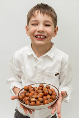 A little boy holding a plate of nuts on a white background. High quality photoの写真素材