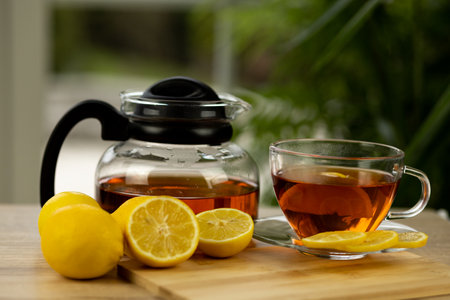 Glass cup of tea, teapot, sliced lemons on the table. Kettle with tea. Lemon tea. High quality photoの写真素材