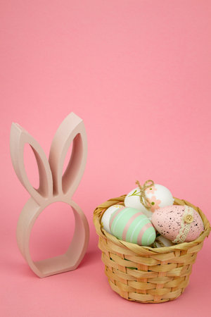 Easter eggs in a wicker basket on a pink background. Easter eggs and a bunny. High quality photoの写真素材