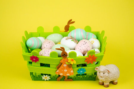 Colorful Easter eggs in a green basket on a yellow background. Easter festival. High quality photoの写真素材