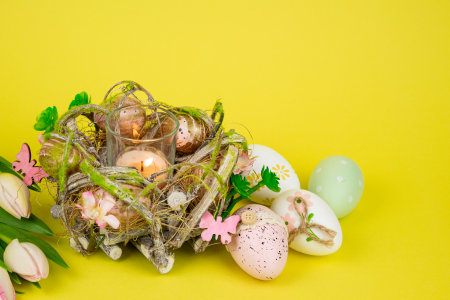 Easter eggs and a candle. View from above. Easter colorful eggs on a yellow background. High quality photoの写真素材