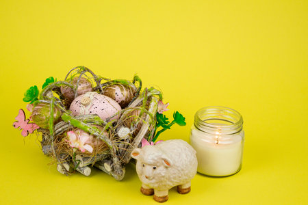 Easter eggs and a sheep on a yellow background. Statuette of a sheep next to Easter eggs. High...