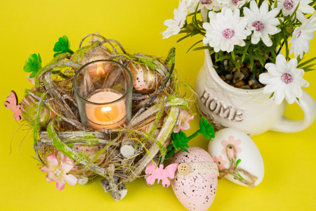 Easter eggs and a candle. View from above. Easter colorful eggs on a yellow background. High quality photoの写真素材