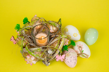 Easter eggs and a candle. View from above. Easter colorful eggs on a yellow background. High quality photoの写真素材