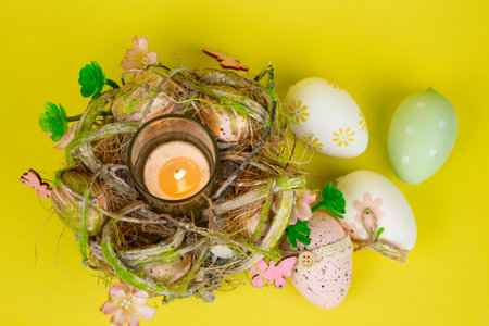 Easter eggs and a candle. View from above. Easter colorful eggs on a yellow background. High quality photoの写真素材