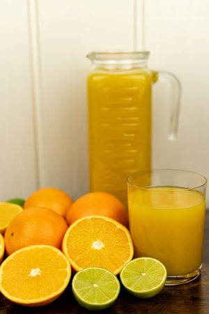 Cut oranges and limes on the table. A glass of citrus juice. Freshly squeezed orange juice. High quality photoの写真素材