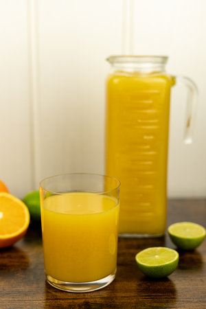 Cut oranges and limes on the table. A glass of citrus juice. Freshly squeezed orange juice. High quality photoの写真素材