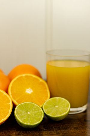 Cut oranges and limes on the table. A glass of citrus juice. Freshly squeezed orange juice. High quality photoの写真素材