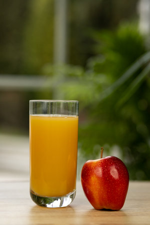 A glass of juice and an apple on the table by the window. Apple and juice. High quality photoの写真素材
