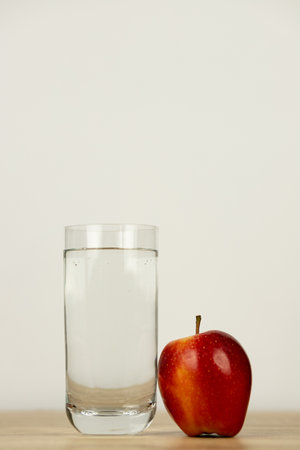An apple and a glass of water on the table. High quality photoの写真素材