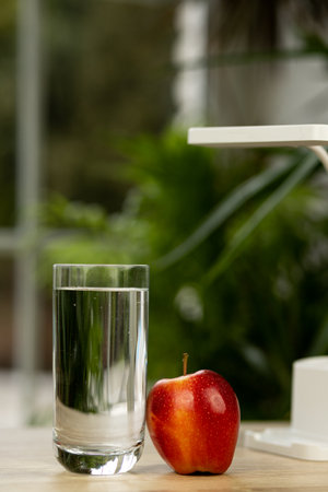 An apple and a glass of water on the table. High quality photoの写真素材