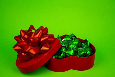 Open red heart-shaped box with close-up candies. Box of chocolates on a green background. High quality photoの写真素材