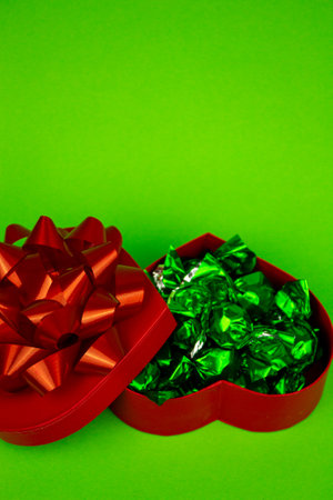 Open red heart-shaped box with close-up candies. Box of chocolates on a green background. High quality photoの写真素材
