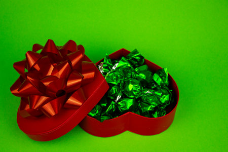Open red heart-shaped box with close-up candies. Box of chocolates on a green background. High quality photoの写真素材