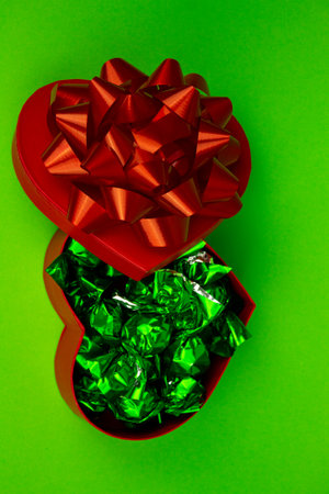 Open red heart-shaped box with close-up candies. Box of chocolates on a green background. High quality photoの写真素材