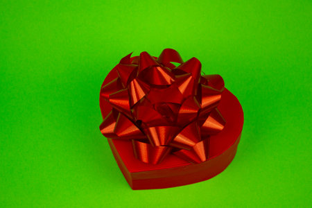 Red heart-shaped box with red bow close-up on green background. High quality photoの写真素材