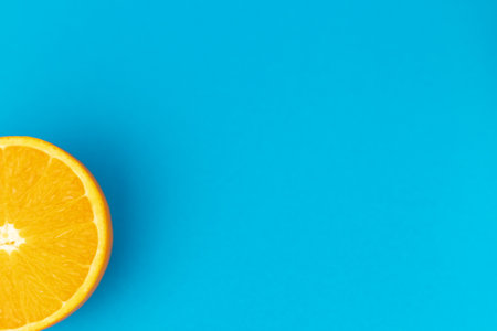 Half an orange on a blue background. Close-up view from above. High quality photoの写真素材