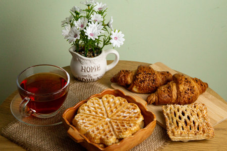 Waffles, croissants and tea. Tea drinking at home. Fresh homemade pastries. Waffle close-up. High quality photoの写真素材