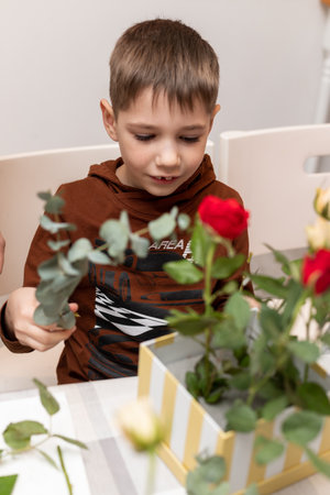 A child makes a handicraft with his own hands for Mother's Day. Boy making a bouquet for his mother. High quality photoの写真素材