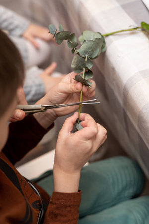 A child makes a handicraft with his own hands for Mother's Day. Boy making a bouquet for his mother. High quality photoの写真素材