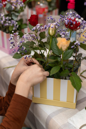 A child makes a handicraft with his own hands for Mother's Day. Boy making a bouquet for his mother. High quality photoの写真素材