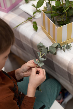A child makes a handicraft with his own hands for Mother's Day. Boy making a bouquet for his mother. High quality photoの写真素材