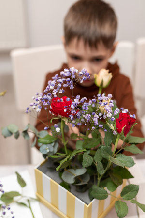A child makes a handicraft with his own hands for Mother's Day. Boy making a bouquet for his mother. High quality photoの写真素材