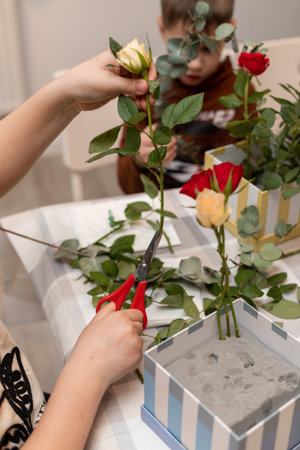 A child makes a handicraft with his own hands for Mother's Day. Boy making a bouquet for his mother. High quality photoの写真素材