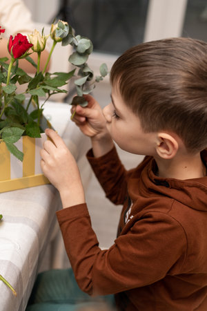 A child makes a handicraft with his own hands for Mother's Day. Boy making a bouquet for his mother. High quality photoの写真素材
