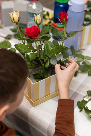A child makes a handicraft with his own hands for Mother's Day. Boy making a bouquet for his mother. High quality photoの写真素材