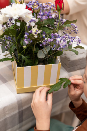A child makes a handicraft with his own hands for Mother's Day. Boy making a bouquet for his mother. High quality photoの写真素材