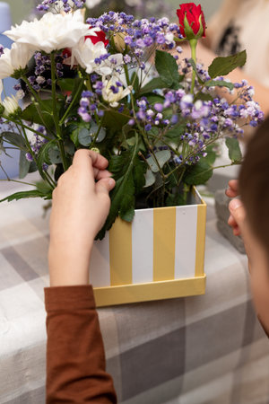 A child makes a handicraft with his own hands for Mother's Day. Boy making a bouquet for his mother. High quality photoの写真素材