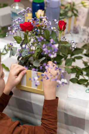 A child makes a handicraft with his own hands for Mother's Day. Boy making a bouquet for his mother. High quality photoの写真素材