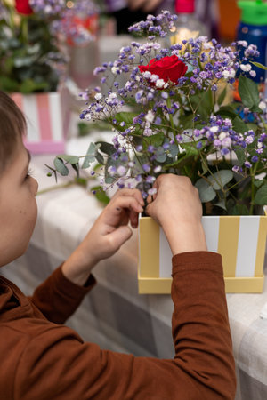 A child makes a handicraft with his own hands for Mother's Day. Boy making a bouquet for his mother. High quality photoの写真素材
