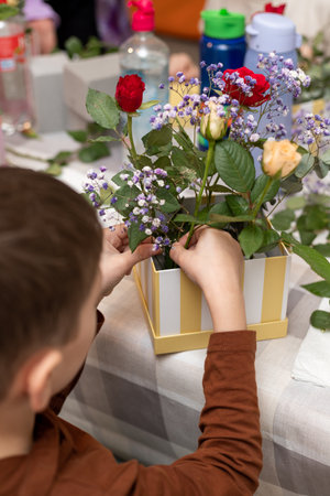 A child makes a handicraft with his own hands for Mother's Day. Boy making a bouquet for his mother. High quality photoの写真素材
